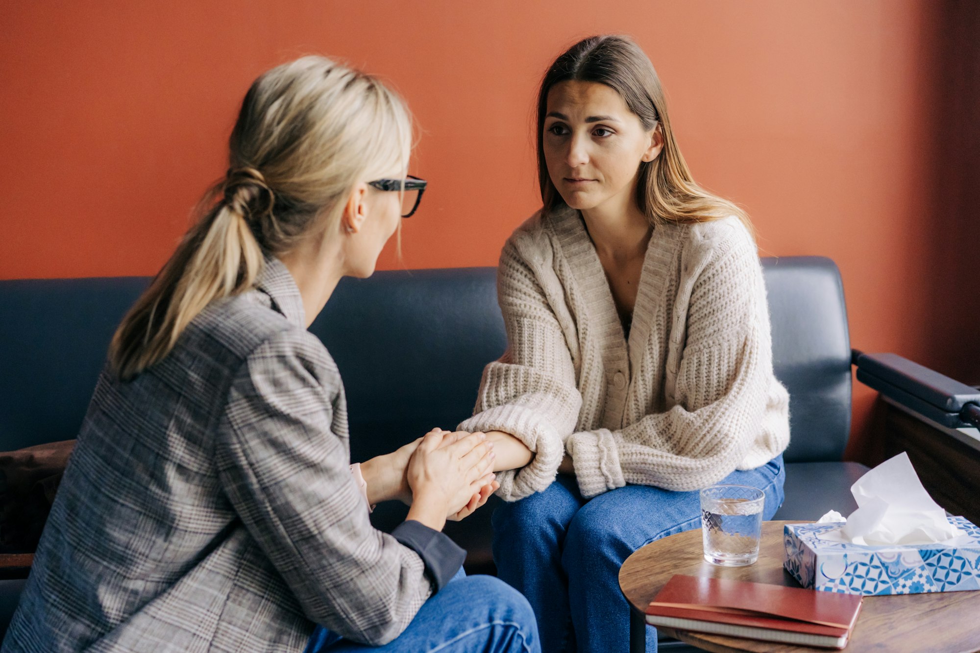 Woman psychotherapist holding the hand of a woman client supports and comforts.